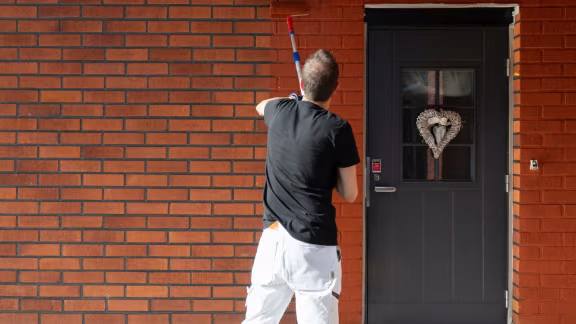 Painter painting a brick house