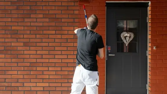 Painter painting a brick house