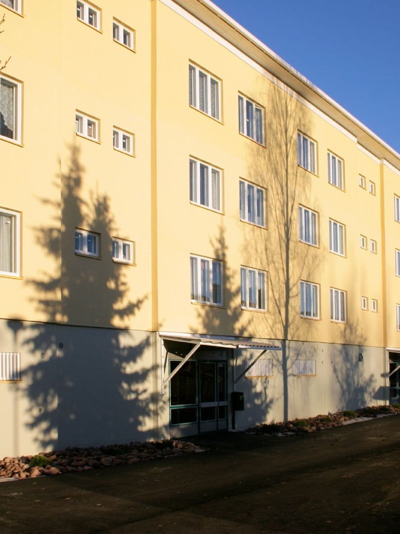 Vaaleankeltainen kiviainesjulkisivu kerrostalossa.
