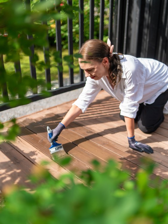 Nainen öljyämässä terassilautoja