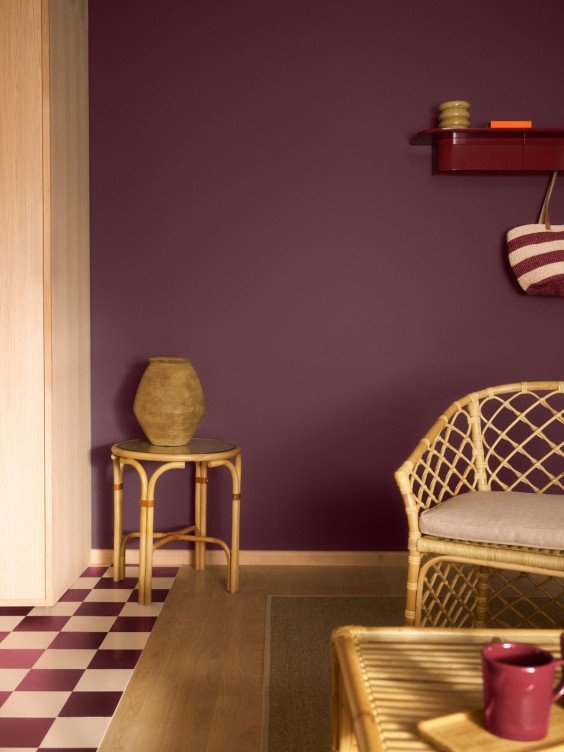 Luumuinen seinä, edessä puisia kalusteita ja viininpunaisia yksityiskohtia.