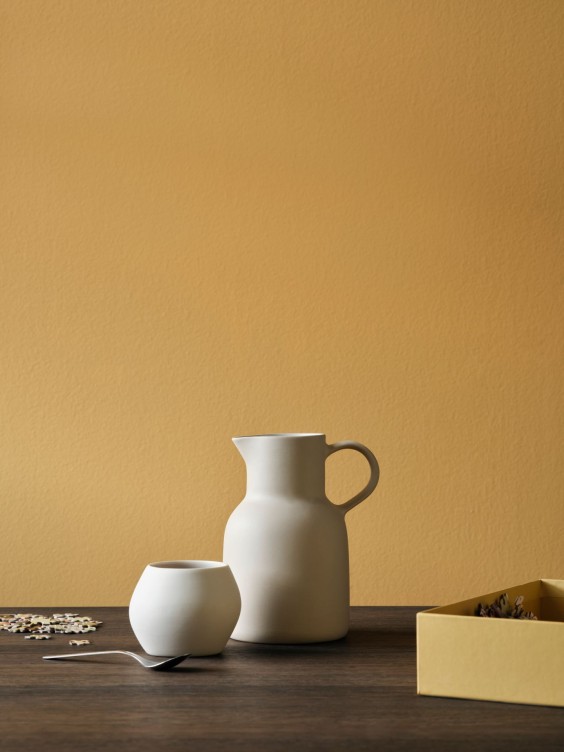 Aurelle-sävy seinällä. Edessä keraaminen kannu.