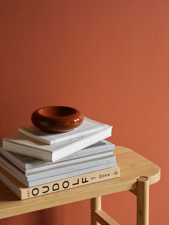 Embera-sävy seinällä. Sivupöydällä pino kirjoja.