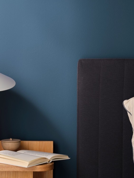 Mariven makuuhuoneen seinällä. Sänky, yöpöytä ja valaisin.