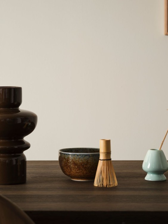 Mellora seinällä. Edessä tumma pöytä, jossa lasimaljakoita.