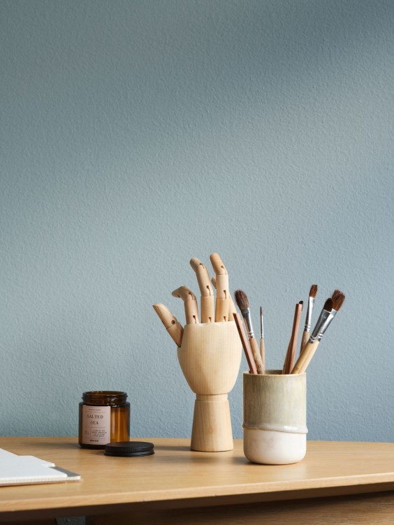 Mute Ocealis seinällä. Edessä pöydällä maalaustarvikkeita.