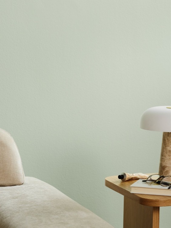 Serevine-sävy seinällä. Edessä sohvan kulma ja pöytä jossa valaisin.