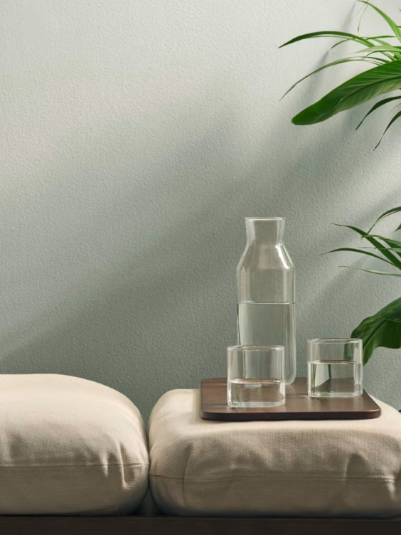 Thalora-sävy seinällä. Edessä daybed ja vihreä huonekasvi.