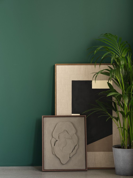 Verdalis-sävy seinällä. Edessä taidetta ja huonekasvi.