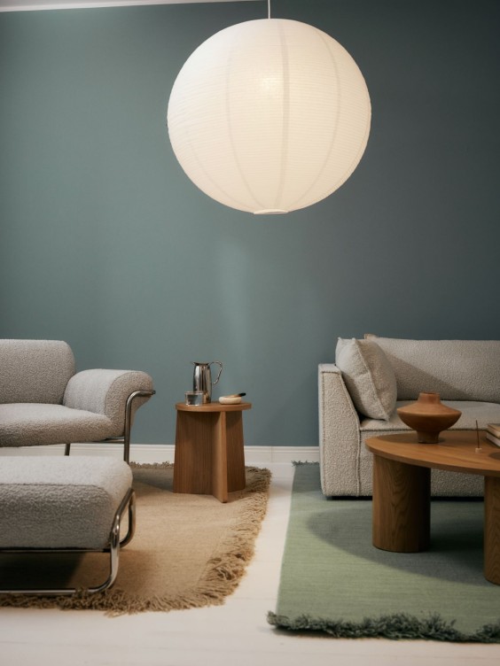 Sohvaryhmä ja lukunurkkaus, jotka erottelee toisistaan eri väriset matot. Katossa suuri paperivalaisin.