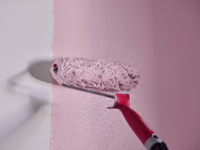 Maalitela maalaa vaaleanpunaista seinään
