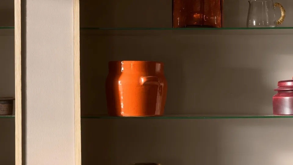 Keittiön hyllykkö, jossa oranssin ja beigen sävyisiä astioita.