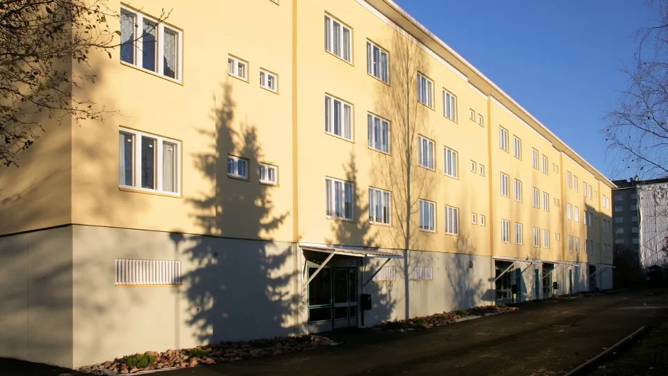 Vaaleankeltainen kiviainesjulkisivu kerrostalossa.