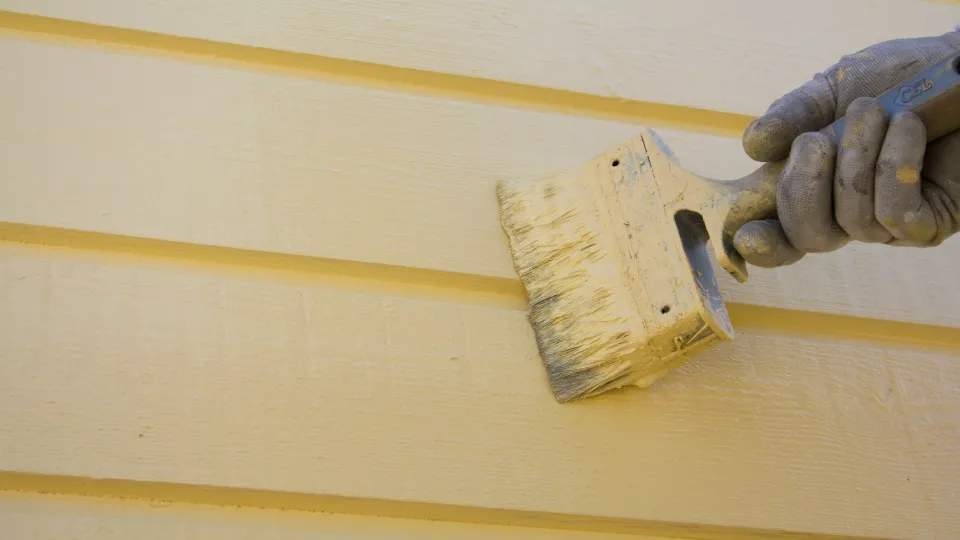 Puutaloa maalataan keltaisella