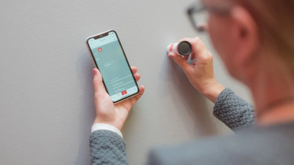 Nainen mittaa seinäväriä Tikkurilan Color Reader värimittarilla