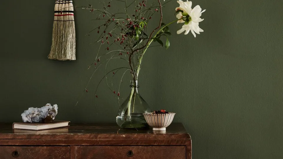 syvänvihreä seinä ja ruskea lipasto