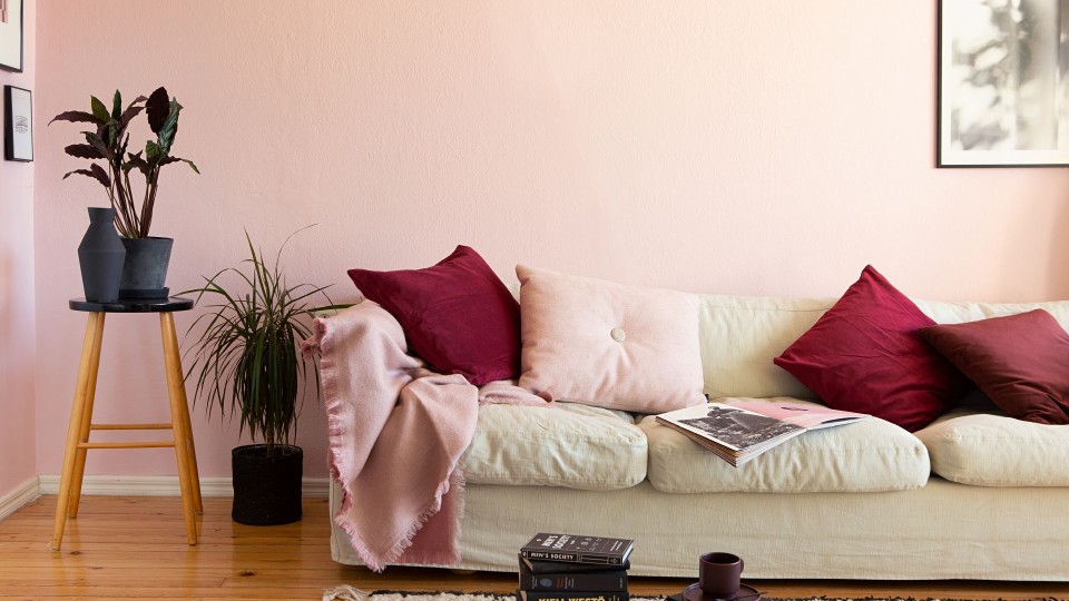 Vaaleanpunaiseksi maalattu olohuone ja vaalea sohva