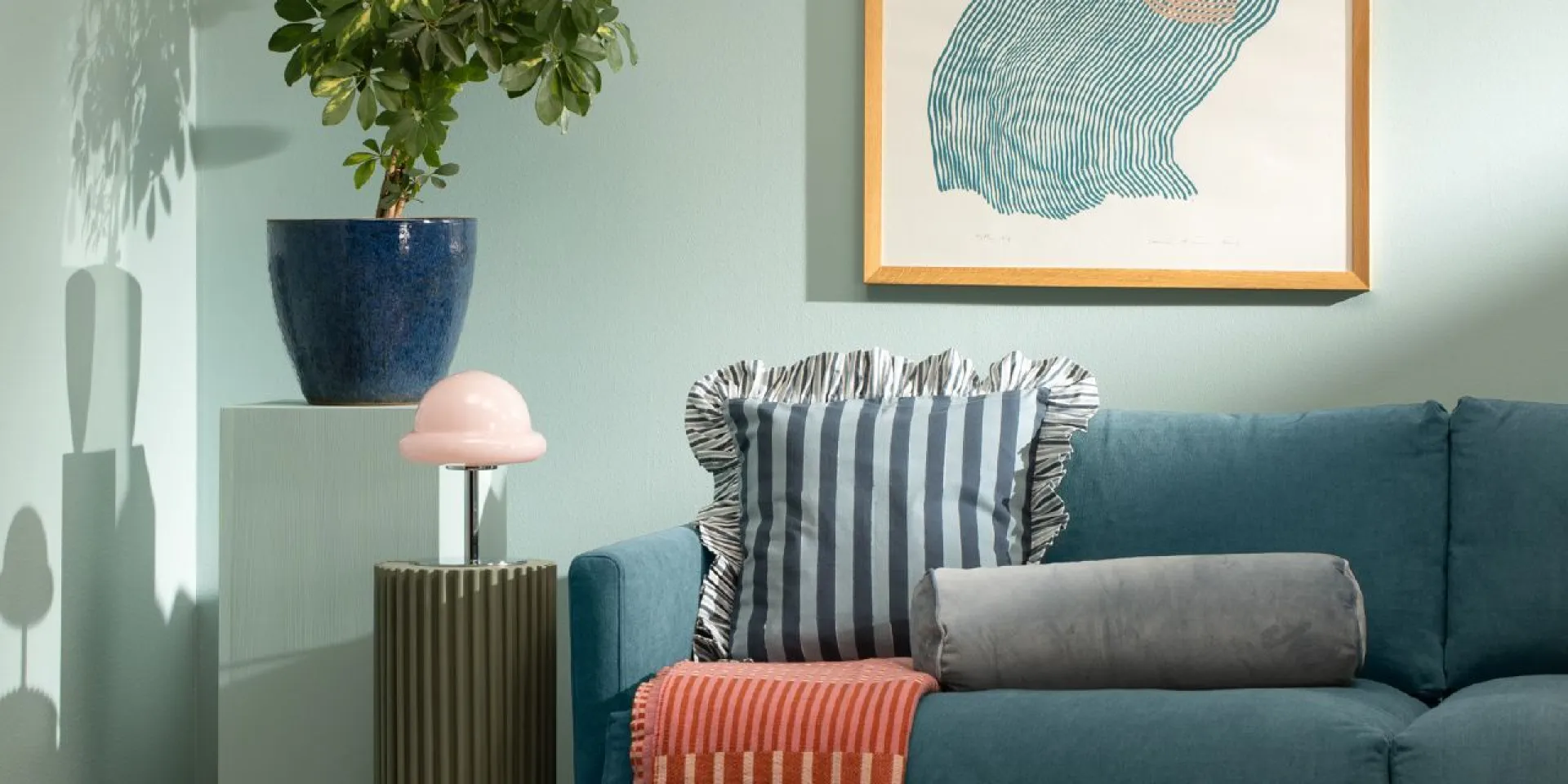 Turkoosi sohva, vihreä seinä jossa taulu seinällä. 