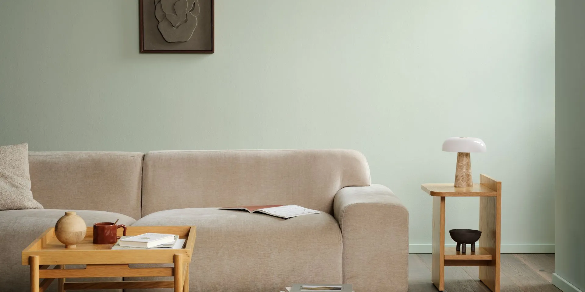 Mute Serevine -sävyinen vihertävä seinä. Edessä sohva ja koivun sävyiset pöydät.