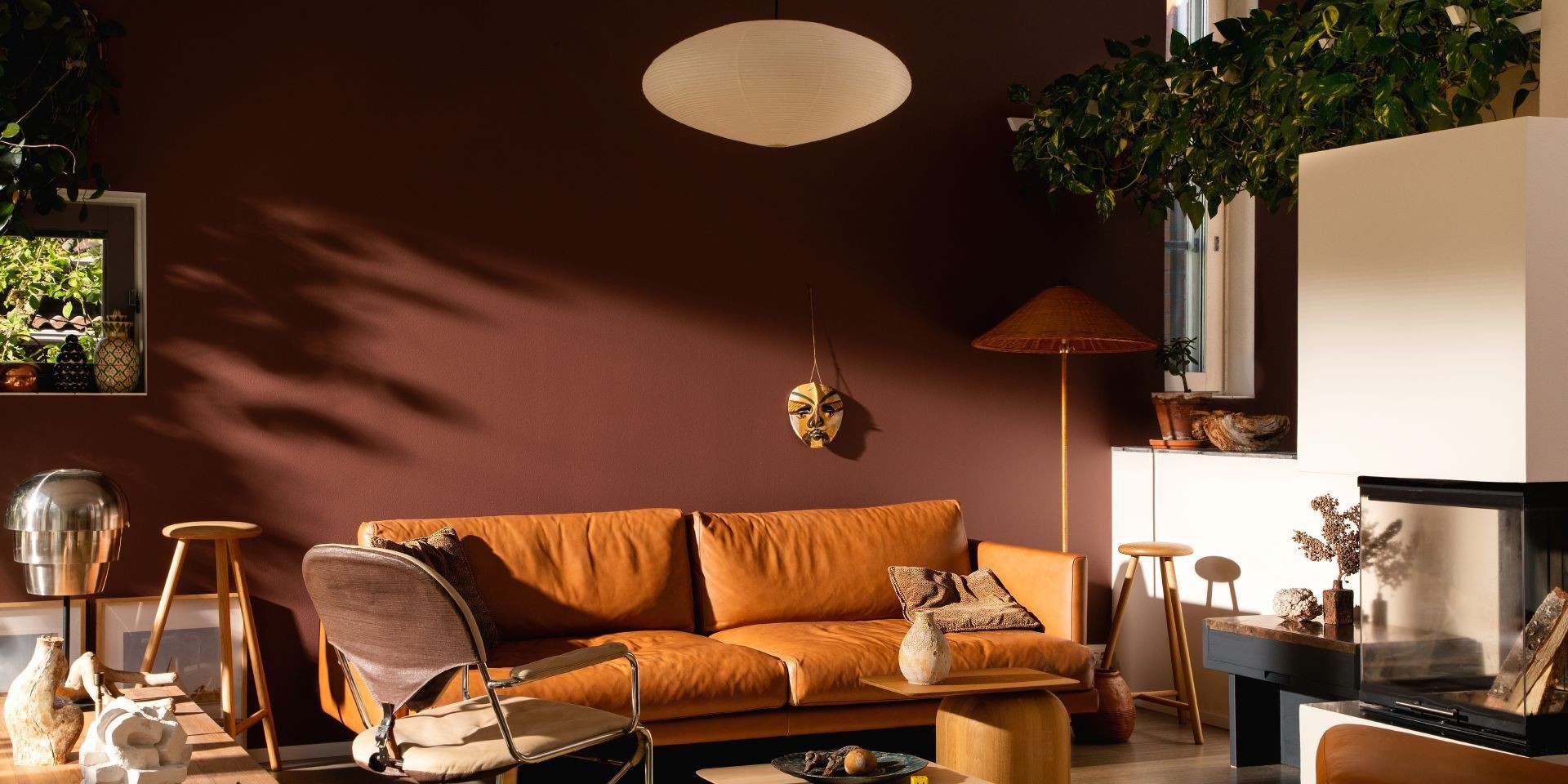 Lämpimän ruskean sävyinen seinä ja ruskea nahkasohva olohuoneessa