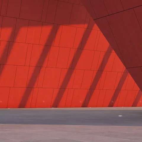 Punainen seinä, jossa näkyy valon ja varjon eroja.