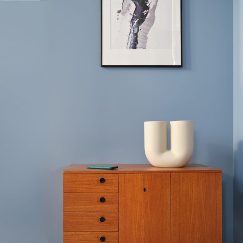 Sininen seinä ripauksella harmaata olohuoneessa ja puinen lipasto