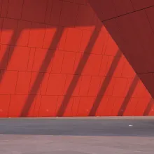 Punainen seinä, jossa näkyy valon ja varjon eroja.