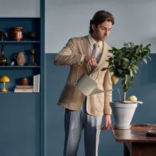 Mies kastelee sitruunapuuta sinisessä huoneessa