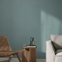 Rauhallinen olohuone, jossa seinällä Mute syvämattamaali. Edessä vaalea sohva, tuoli ja pieni sivupöytä.