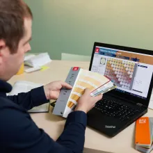 Suunnittelijalla Tikkurila Facade väriviuhka kädessä ja Building Coach ohjelmisto auki tietokoneella.