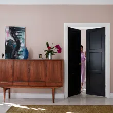 Olohuone, jossa roosa seinä ja puinen senkki