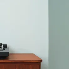 Kaksivärinen vihreä seinä, jossa puinen lipasto ja vinyylisoitin