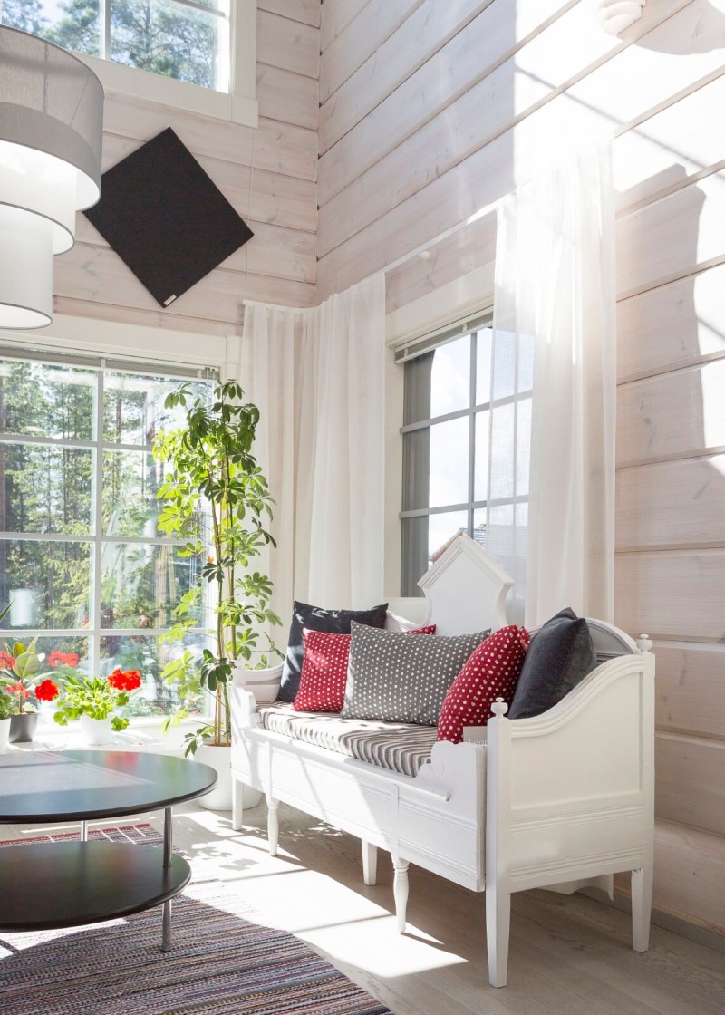Hirsitalon olohuone, vaaleat seinät ja puinen sohva