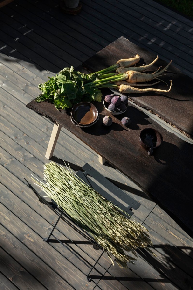 Valtti Plus Terrace Oililla käsitellyn terassipöydän päällä palsternakkaa ja muita vihanneksia.