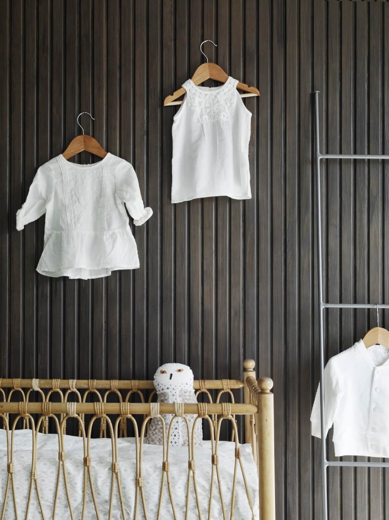 Vauvanhuone, tummanharmaa seinä, pinnasänky ja valkoiset paidat seinällä
