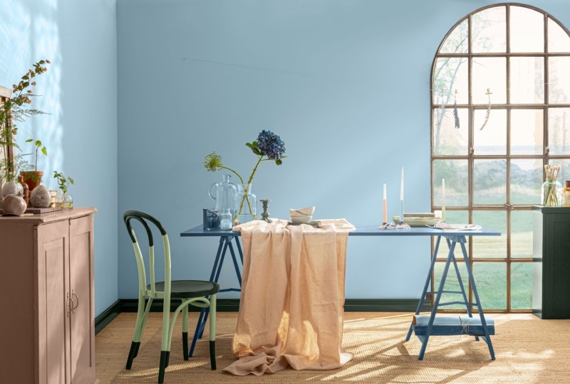 sininen seinä ja vihreäksi maalattu ruokapöytä tuoleilla