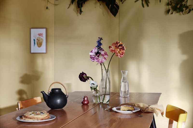 Keltaiseksi maalattu seinä ja puinen ruokapöytä
