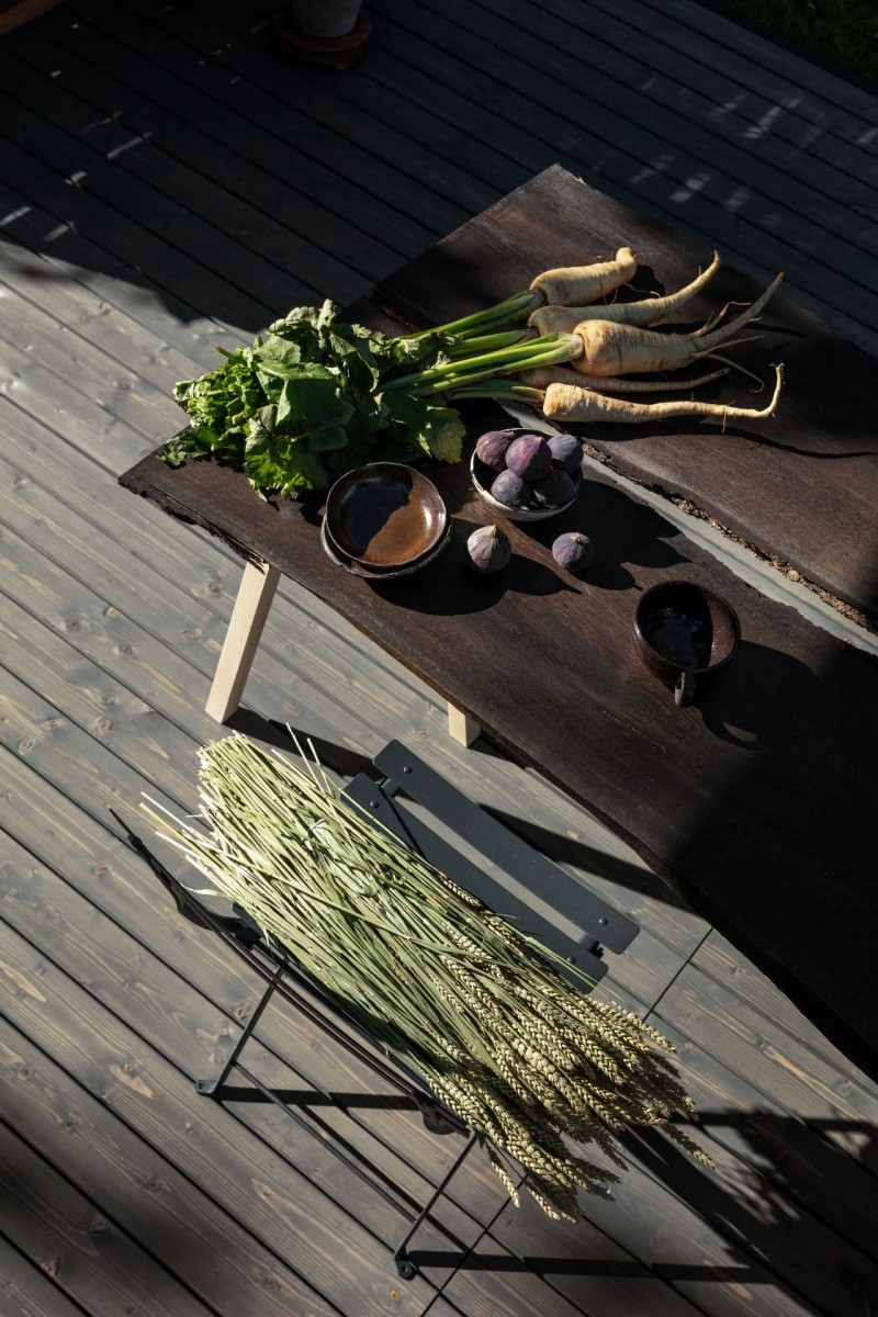 tumma puinen lankkupöytä terassilla sekä vihanneksia ja kasveja