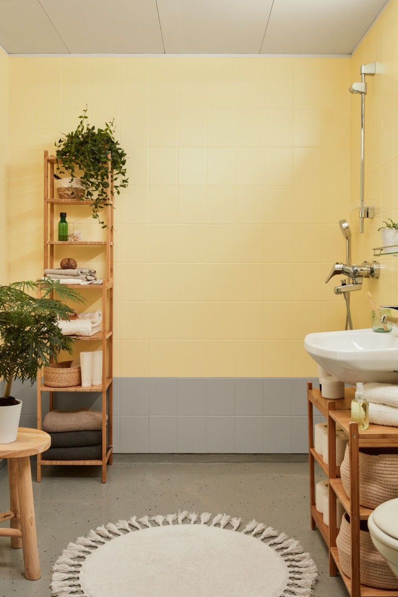 Kirkas kylpyhuone maalattu keltaisella ja harmaalla sävyllä