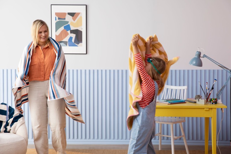 Äiti ja tytär leikkimässä lastenhuoneessa, jossa sininen paneeliseinä